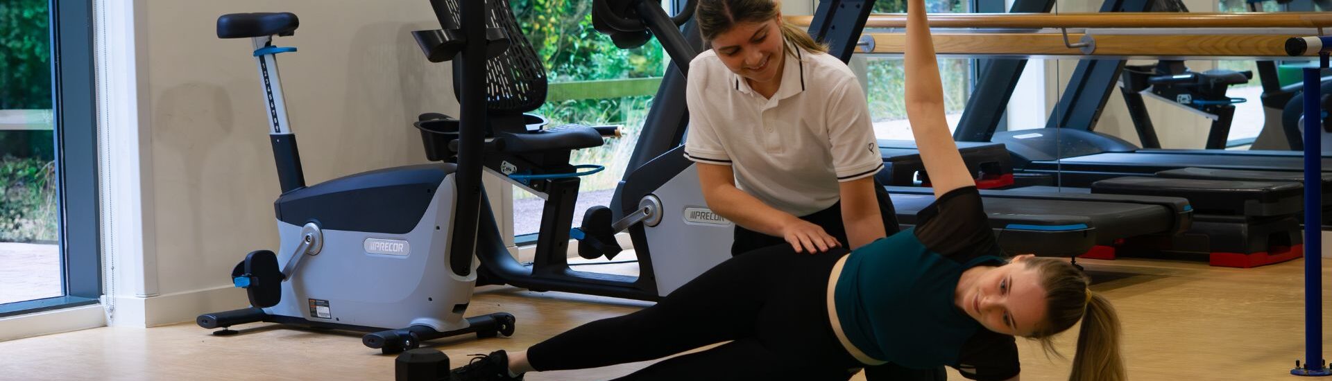 Women lifting a very heavy dumbbell whilst a physiotherapist assesses
