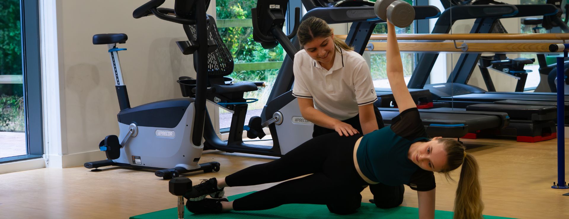 Women lifting a very heavy dumbbell whilst a physiotherapist assesses