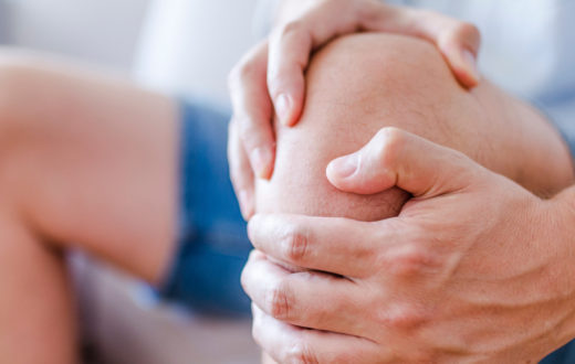 Close up of patient holding knee to relieve knee pain