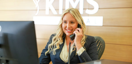 A receptionist smiling while taking a phone call.