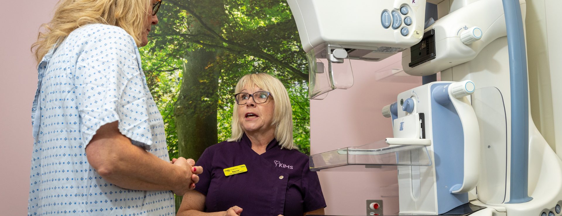 Woman being talked through the process of having a mammogram.