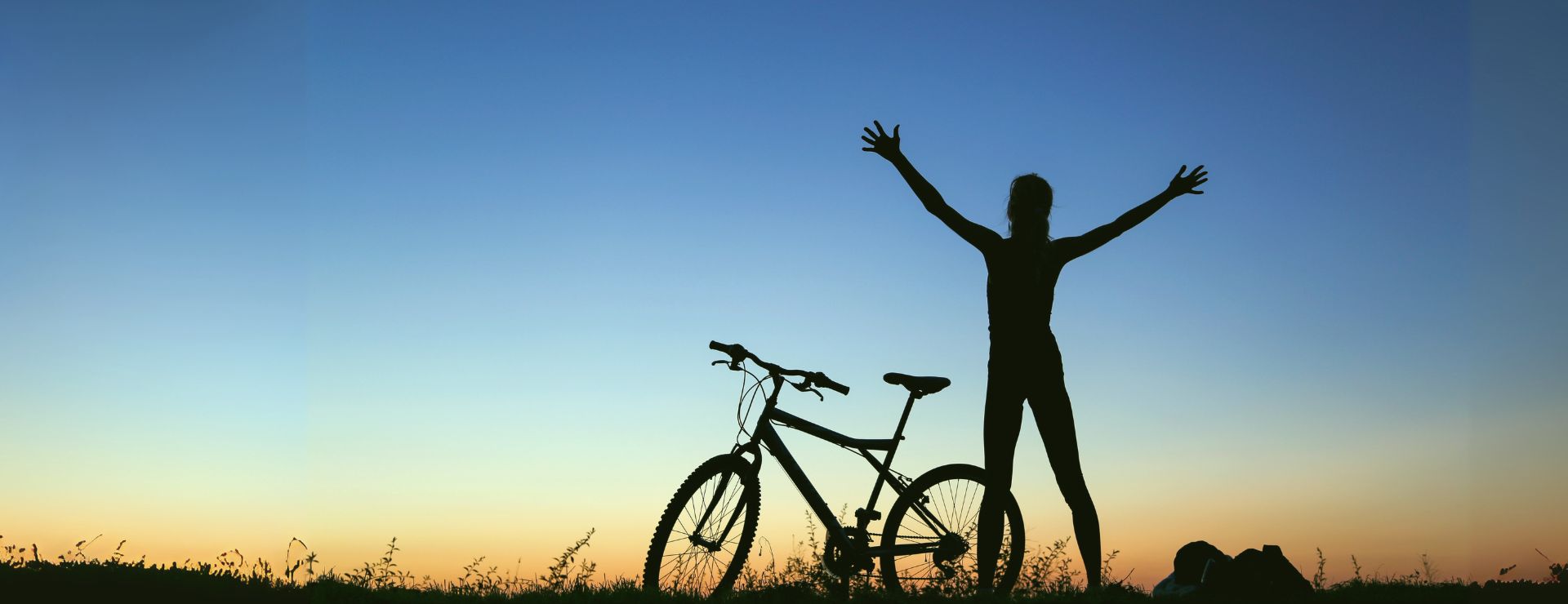 Silhouette of a person with a bicycle at sunrise, celebrating health and wellbeing - KIMS Hospital health checks in Kent