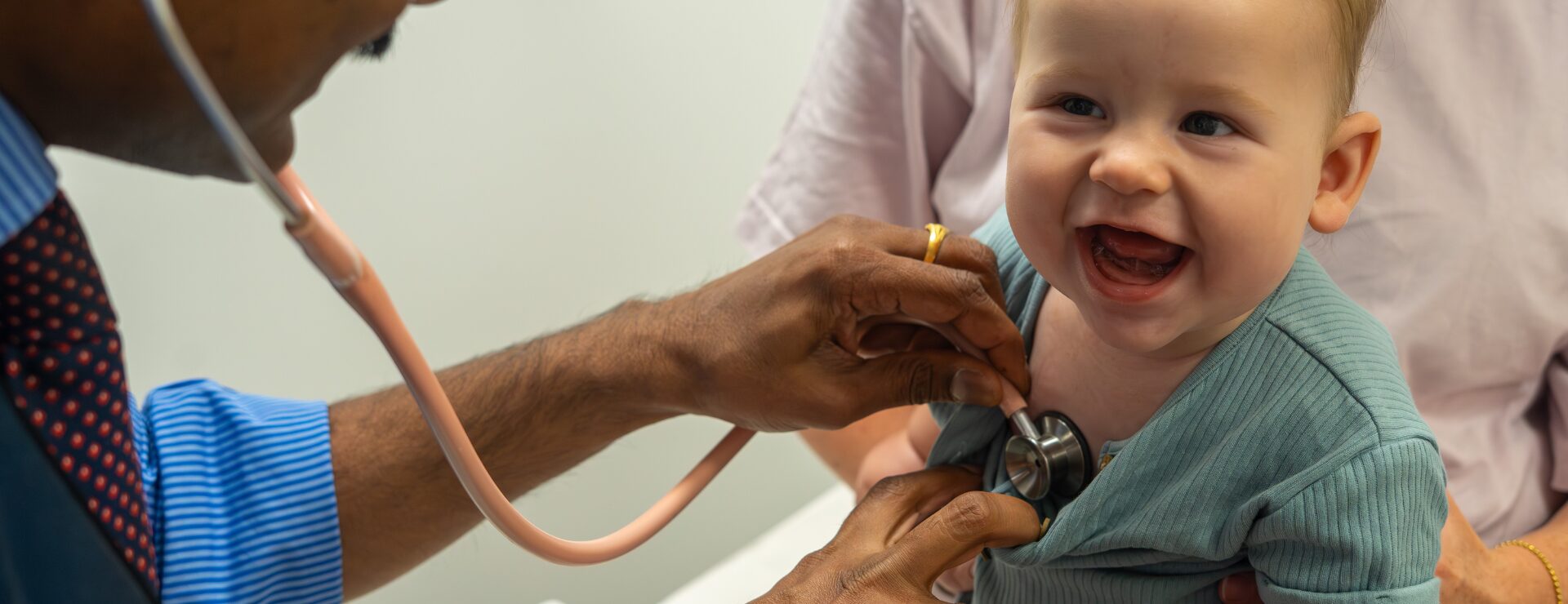 Family GP listening to baby's heartbeat with stethoscope