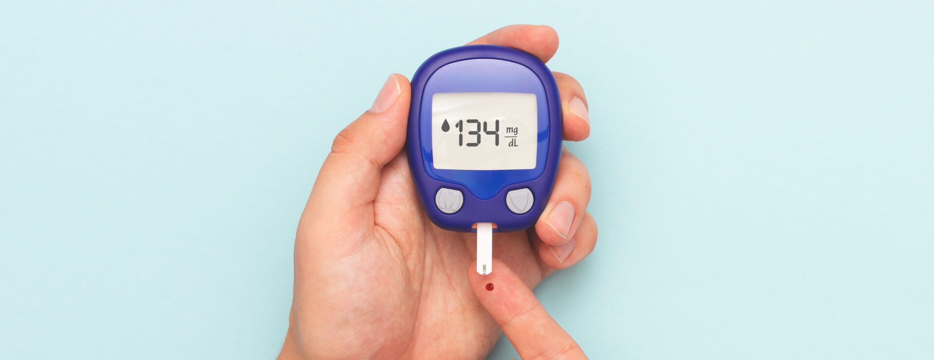 Close-up of a person using a blood glucose monitor to check blood sugar levels, highlighting the importance of early detection and awareness of Type 2 diabetes.