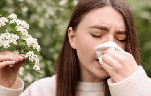 Woman experiencing hay fever symptoms with blossom pollen in spring