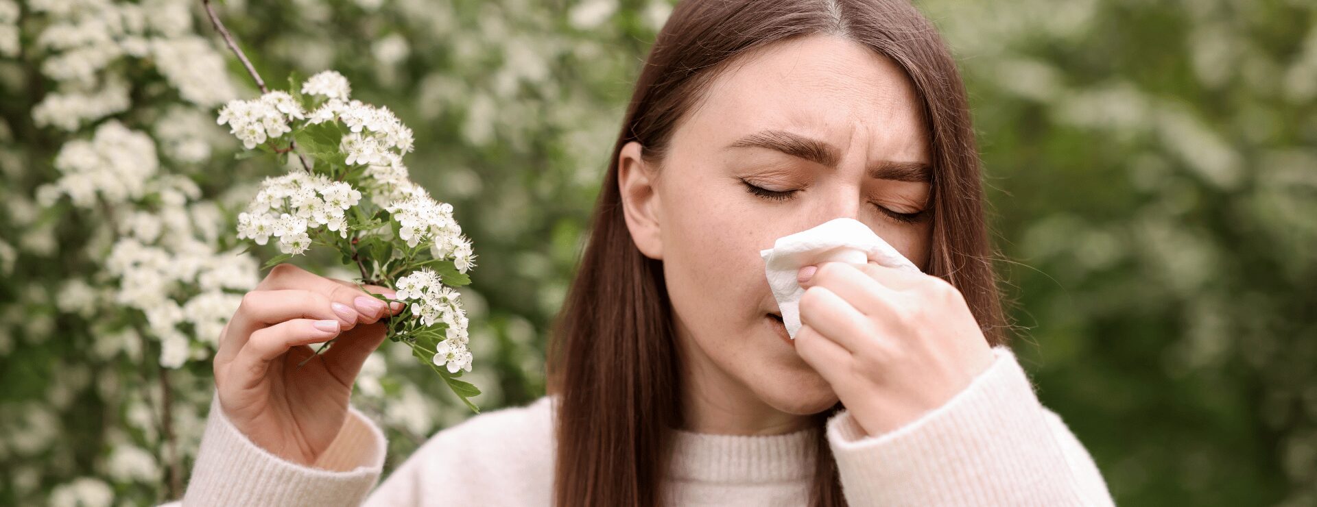 Woman experiencing hay fever symptoms with blossom pollen in spring