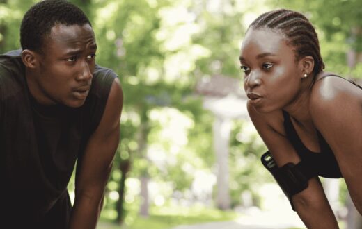 wo runners outdoors, a man supporting a woman who is out of breath after exercise