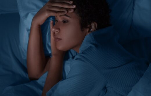 Woman laying awake in bed at night not being able to sleep.